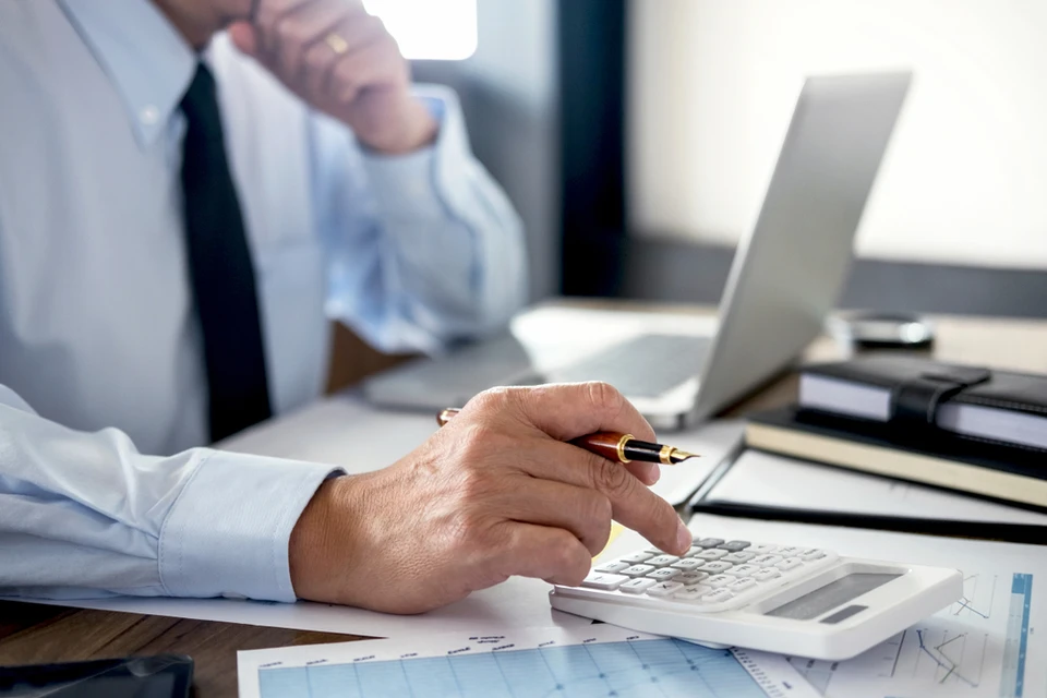 Réunion de travail en intérieur avec trois personnes analysant des rapports financiers sur table en bois